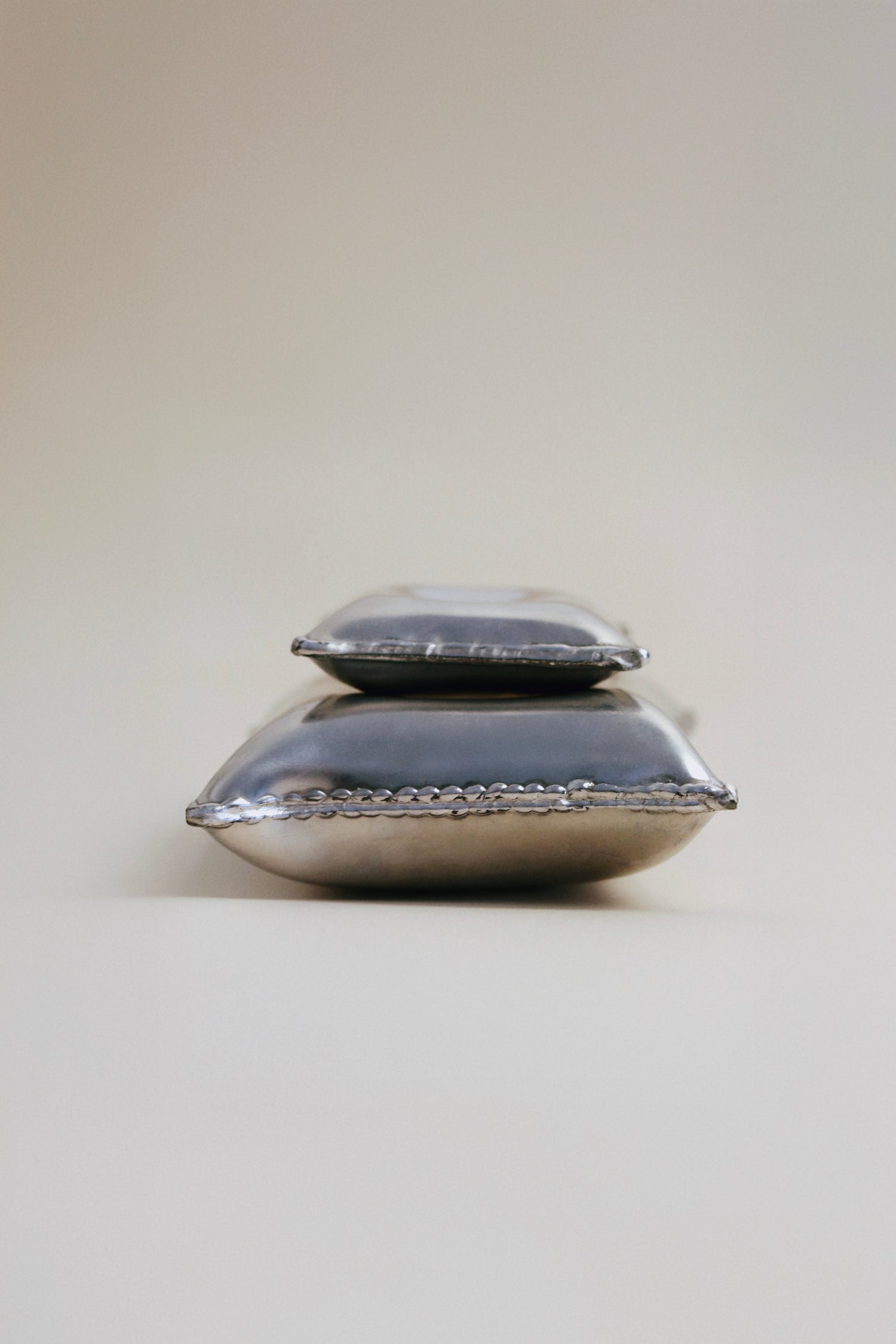 Detail of two decorative pillows with shiny silver surface, perfect for home decor and aesthetic styling.